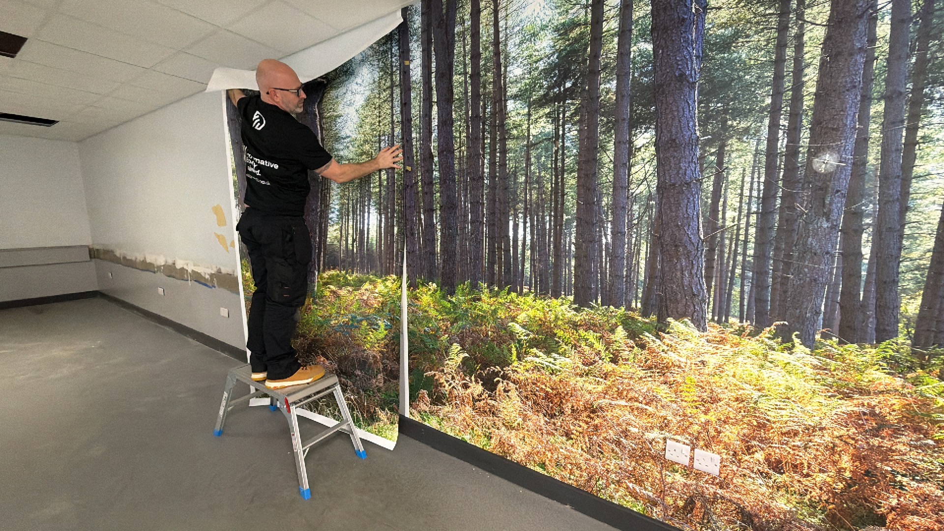 Chris Pitts installing a forest mural